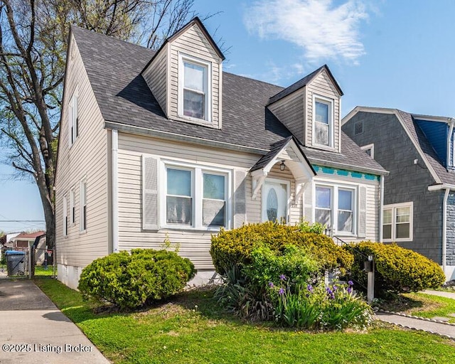 cape cod-style house with a front lawn and roof with shingles