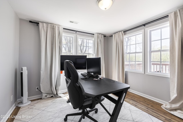 office space with baseboards, light wood-style floors, and visible vents
