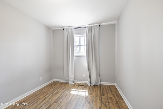 empty room featuring visible vents, baseboards, and wood finished floors