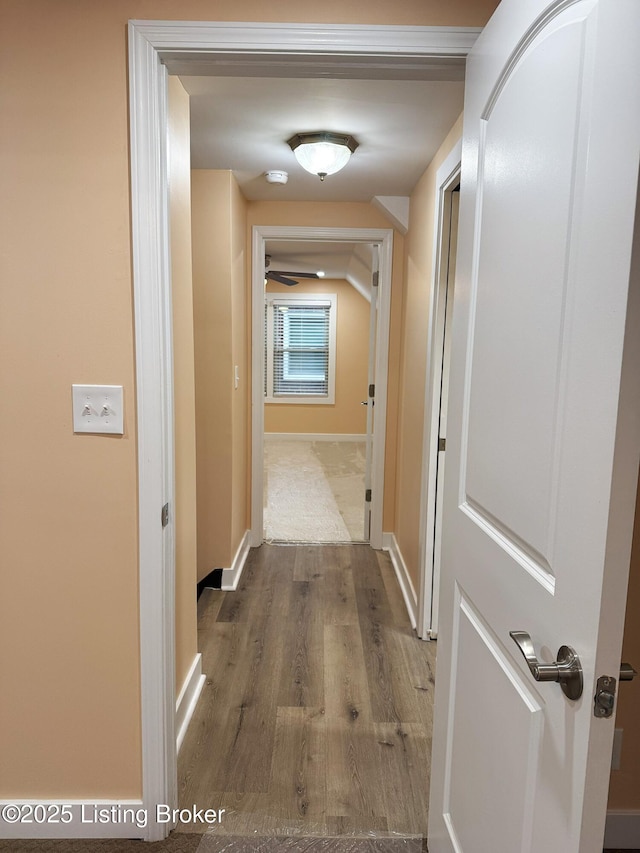 corridor with baseboards and wood finished floors