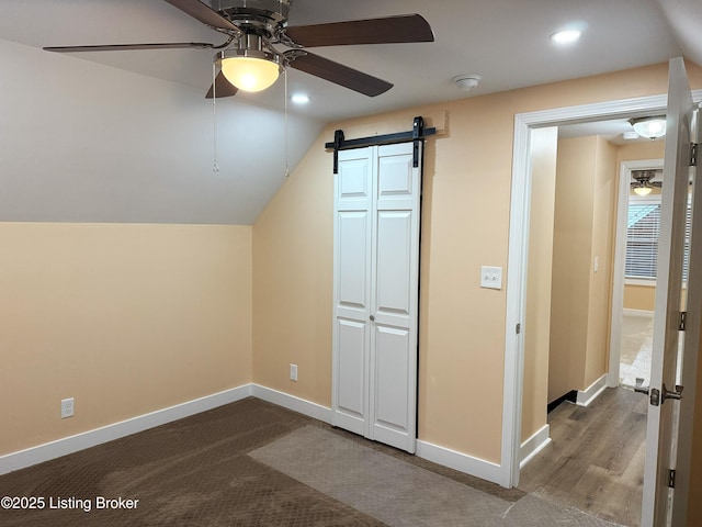 additional living space with lofted ceiling, baseboards, ceiling fan, and a barn door