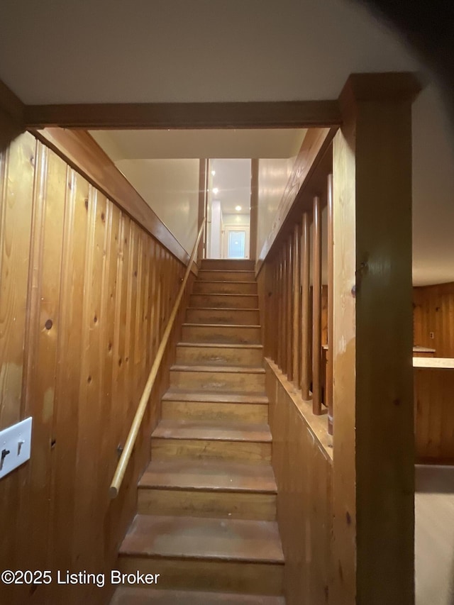 stairway featuring wooden walls