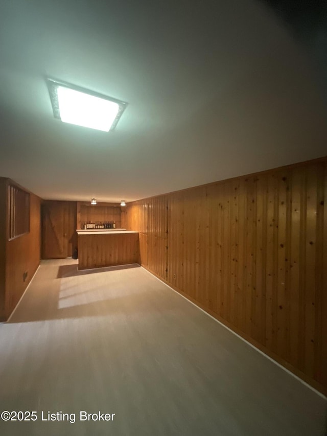 finished below grade area featuring bar area and wood walls