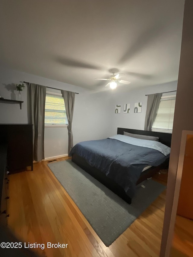bedroom with wood finished floors, visible vents, and ceiling fan