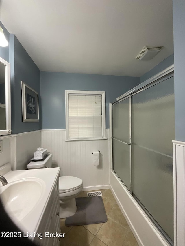 bathroom featuring visible vents, tile patterned floors, a wainscoted wall, and toilet