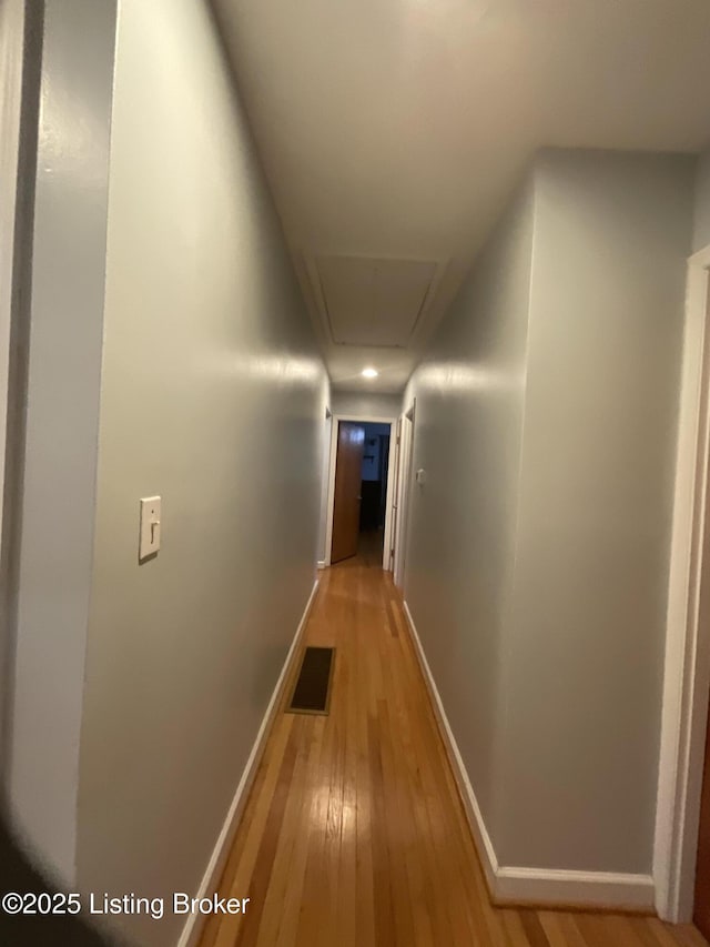 corridor with attic access, baseboards, visible vents, and light wood-style floors