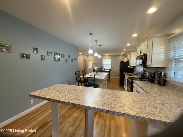 kitchen with black appliances, recessed lighting, a kitchen breakfast bar, and a kitchen island