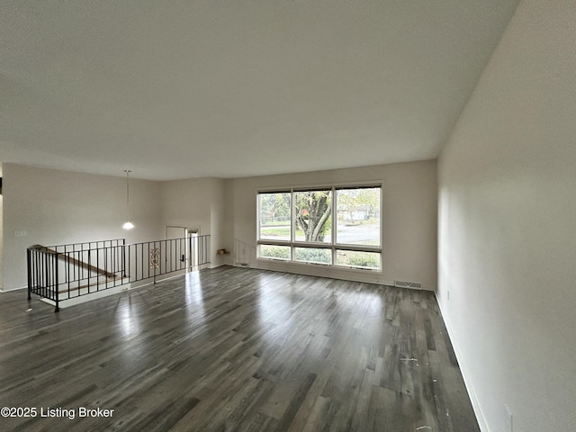unfurnished room with baseboards and dark wood-type flooring