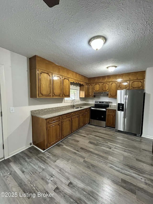 kitchen featuring brown cabinets, appliances with stainless steel finishes, dark wood-type flooring, and a sink