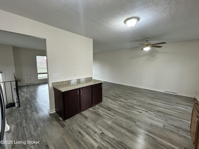 kitchen with a ceiling fan, wood finished floors, a textured ceiling, dark brown cabinetry, and visible vents