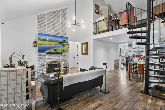 living area featuring baseboards, an inviting chandelier, wood finished floors, a high ceiling, and stairway