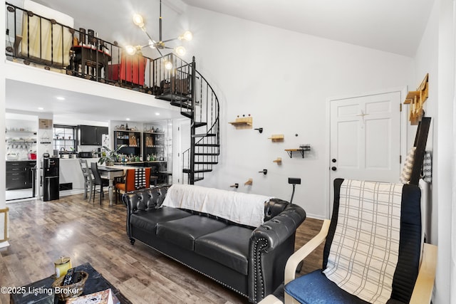 living area with high vaulted ceiling, a chandelier, wood finished floors, and stairs