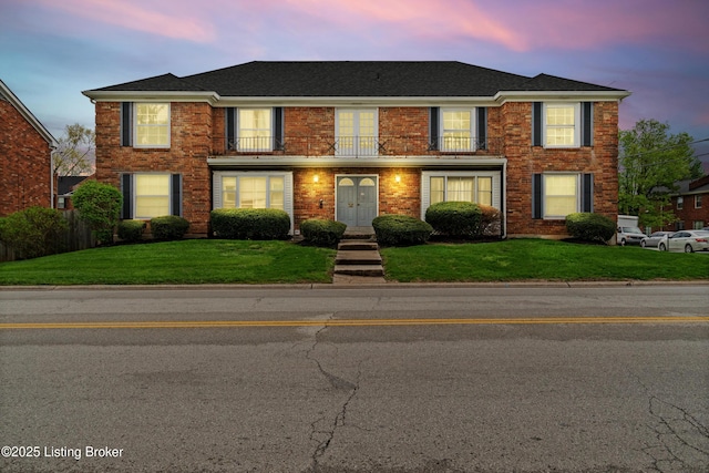 colonial-style house with brick siding, french doors, and a front lawn