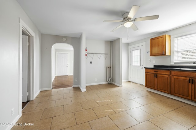 kitchen with light tile patterned floors, radiator heating unit, arched walkways, and ceiling fan