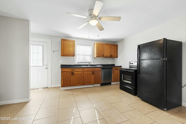 kitchen featuring brown cabinets, dark countertops, a sink, black appliances, and ceiling fan