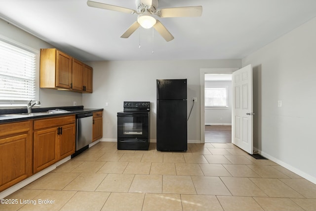 kitchen featuring dark countertops, light tile patterned floors, a sink, black appliances, and brown cabinetry