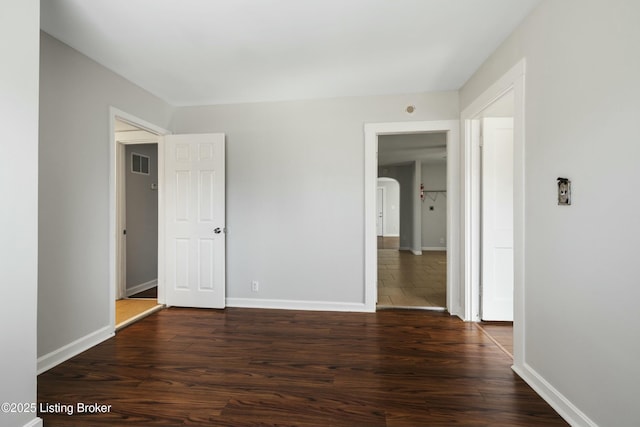 unfurnished bedroom with dark wood finished floors, baseboards, and visible vents