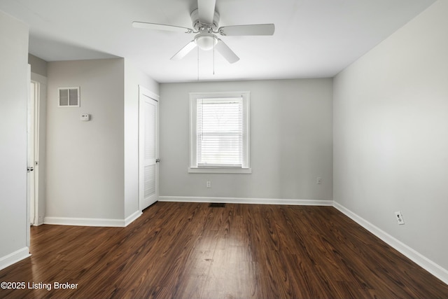 empty room with dark wood-style floors, baseboards, ceiling fan, and visible vents