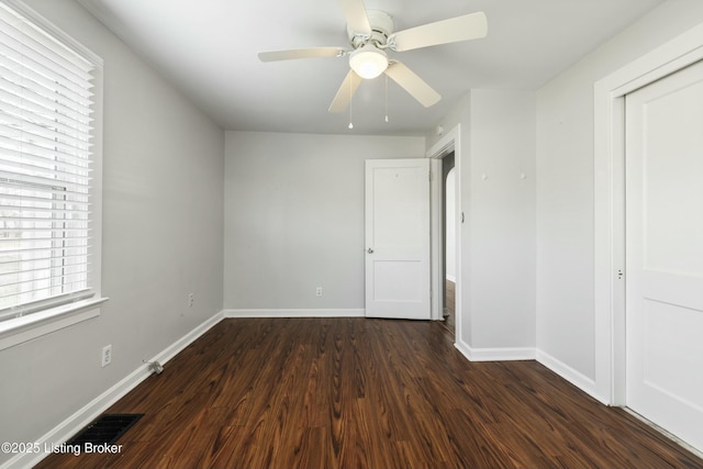 unfurnished bedroom featuring a ceiling fan, baseboards, visible vents, and dark wood-style floors