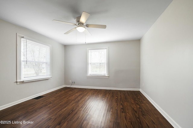 empty room featuring baseboards, visible vents, dark wood-style floors, and ceiling fan
