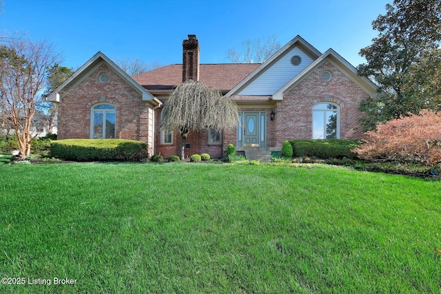 view of front of property featuring a shingled roof, a chimney, brick siding, and a front yard