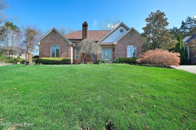 view of front facade with brick siding, roof with shingles, a chimney, and a front lawn