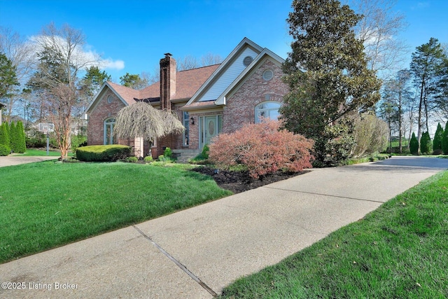 view of front of house with a chimney, a front lawn, and brick siding