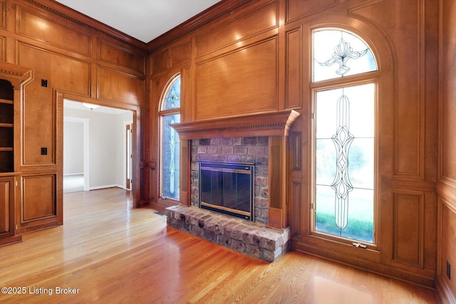 unfurnished living room with a decorative wall, a glass covered fireplace, and light wood-type flooring