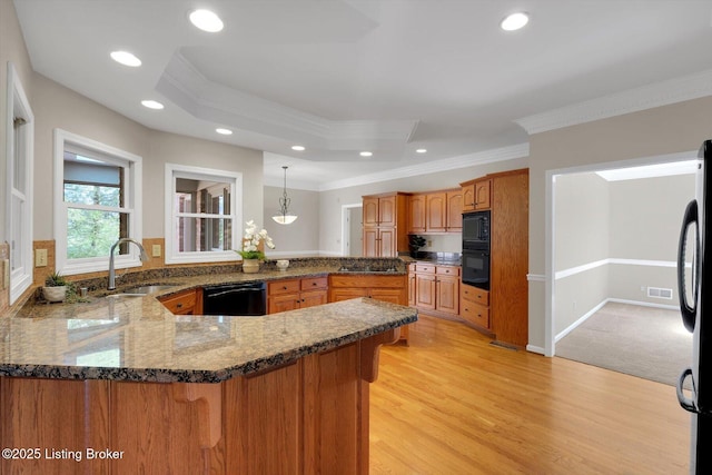 kitchen featuring a peninsula, a sink, dark stone countertops, black appliances, and ornamental molding