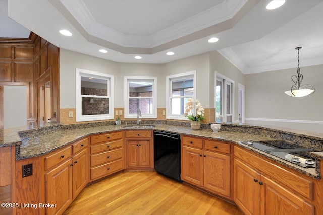 kitchen with a peninsula, light wood finished floors, a sink, and black appliances