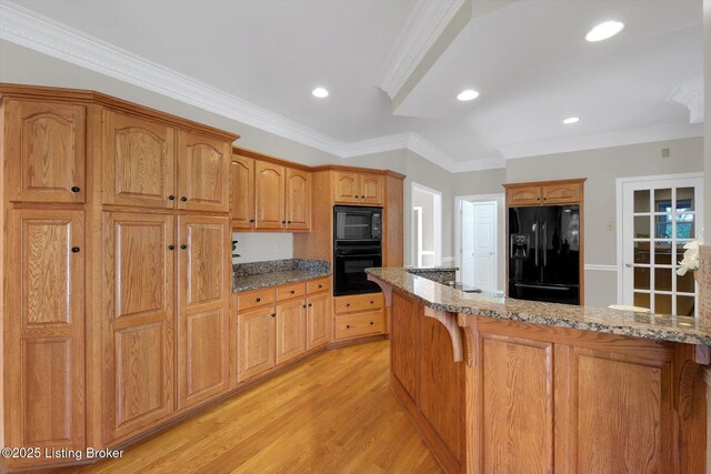 kitchen with light stone countertops, light wood finished floors, and black appliances