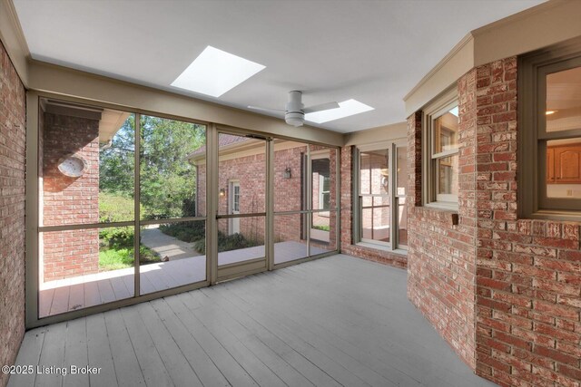 unfurnished sunroom with ceiling fan, a wealth of natural light, and a skylight