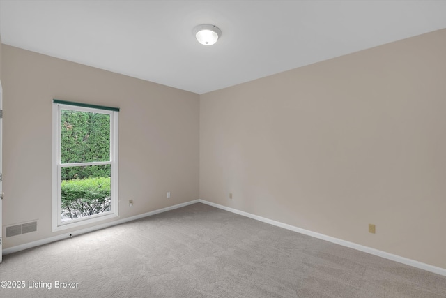 unfurnished room with carpet floors, visible vents, and baseboards