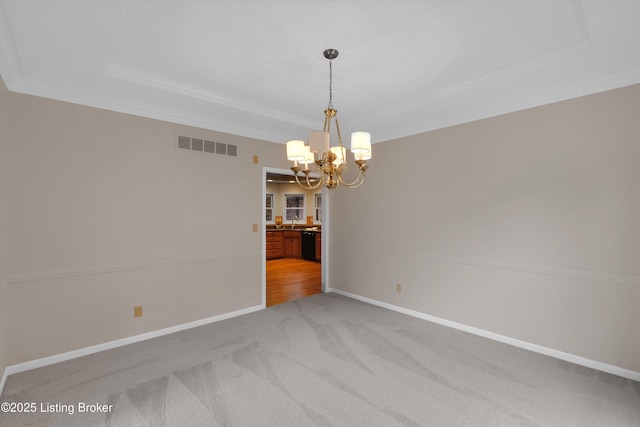 empty room with visible vents, a tray ceiling, a chandelier, and ornamental molding