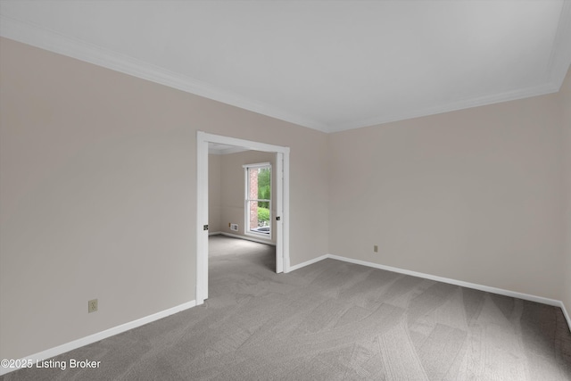 carpeted empty room featuring baseboards and crown molding