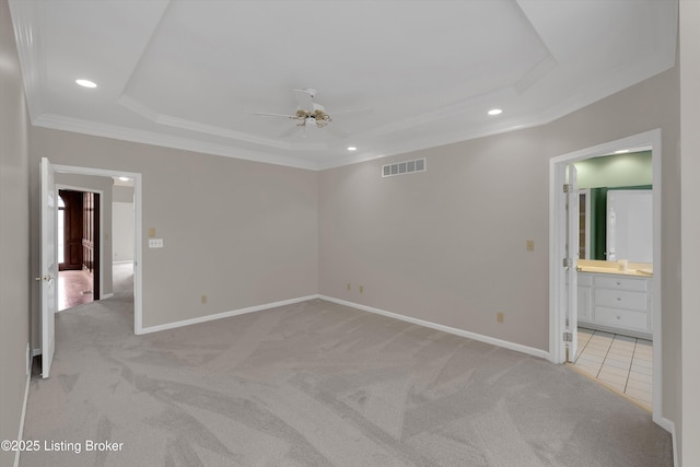 unfurnished bedroom featuring recessed lighting, a tray ceiling, visible vents, ornamental molding, and light carpet