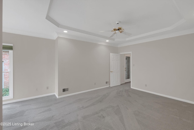 unfurnished room featuring a wealth of natural light, a ceiling fan, visible vents, and a raised ceiling