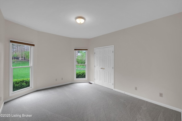 spare room with plenty of natural light, carpet floors, and baseboards