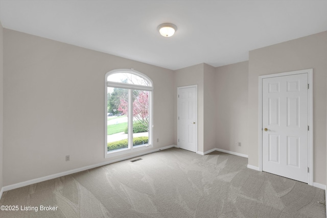 empty room featuring visible vents, carpet flooring, and baseboards