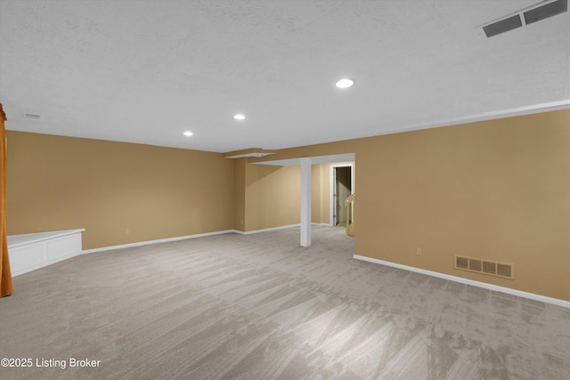 finished below grade area featuring light colored carpet, visible vents, and recessed lighting