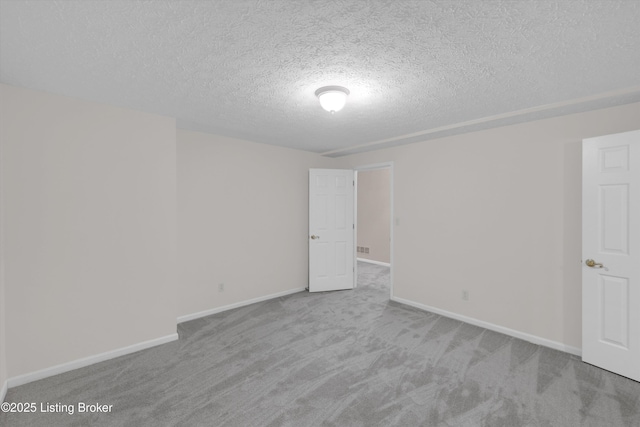 carpeted spare room with a textured ceiling and baseboards