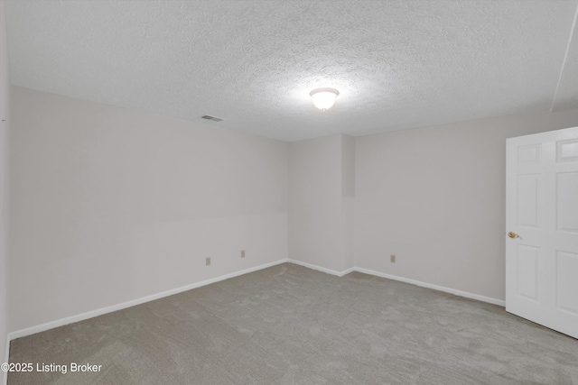 carpeted spare room featuring a textured ceiling, baseboards, and visible vents