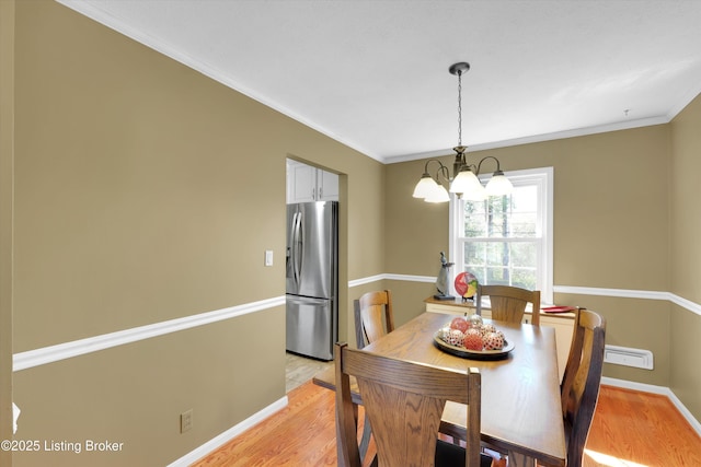 dining area with light wood finished floors, baseboards, a notable chandelier, and ornamental molding