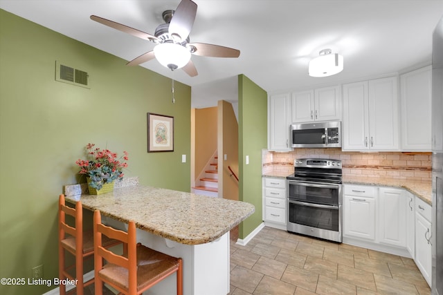 kitchen featuring white cabinets, a peninsula, visible vents, decorative backsplash, and appliances with stainless steel finishes