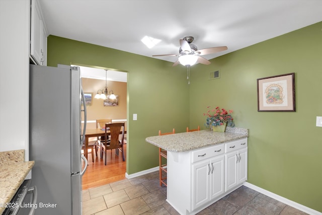 kitchen with ceiling fan with notable chandelier, stainless steel appliances, visible vents, and white cabinetry