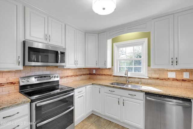 kitchen with appliances with stainless steel finishes, tasteful backsplash, a sink, and white cabinetry