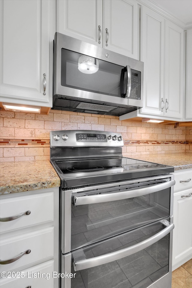 kitchen featuring backsplash, appliances with stainless steel finishes, light stone countertops, and white cabinetry