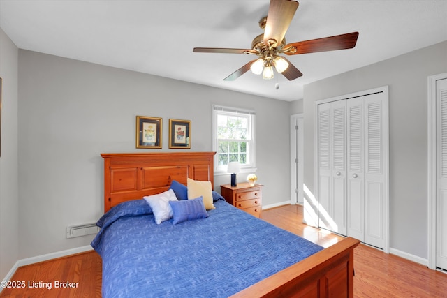 bedroom featuring two closets, light wood finished floors, baseboards, and a ceiling fan