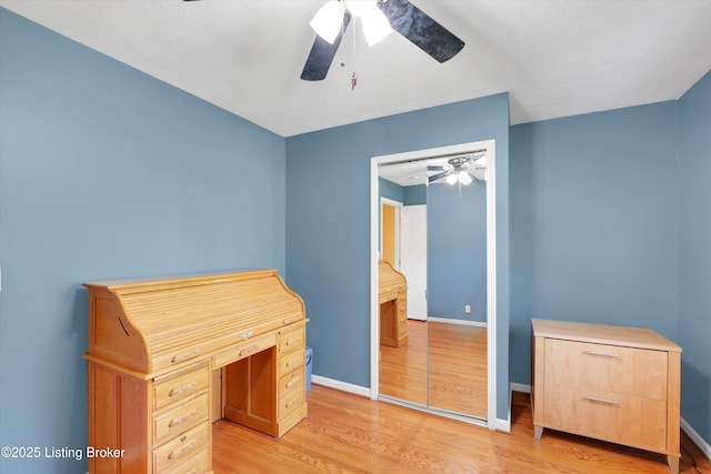 unfurnished office with ceiling fan, baseboards, and light wood-style flooring