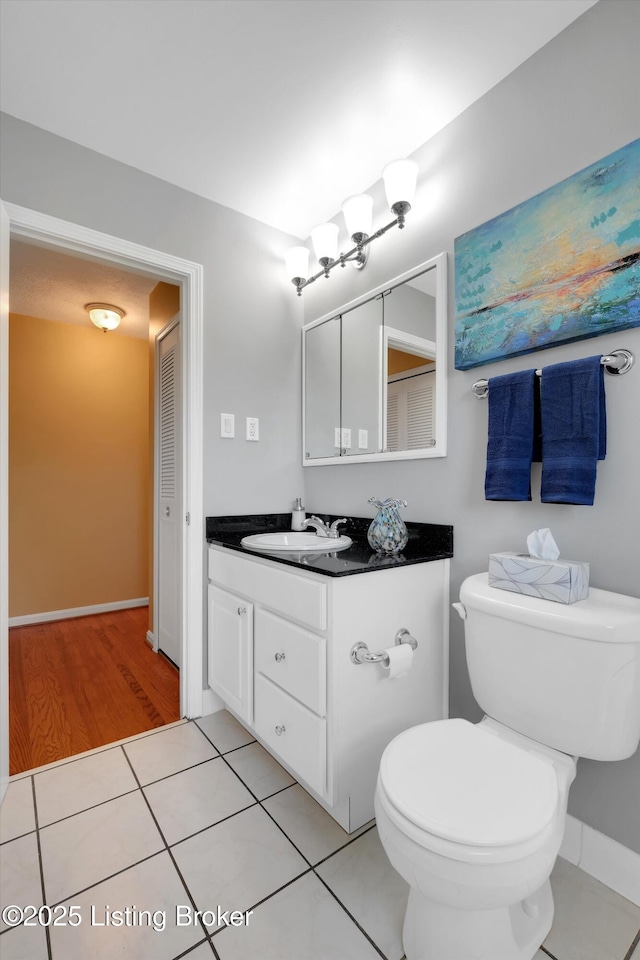 bathroom featuring tile patterned flooring, baseboards, toilet, and vanity